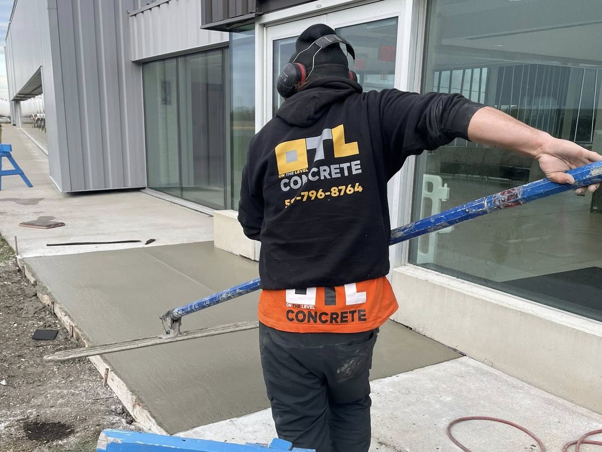 OTL crew member screeding fresh concrete in branded gear