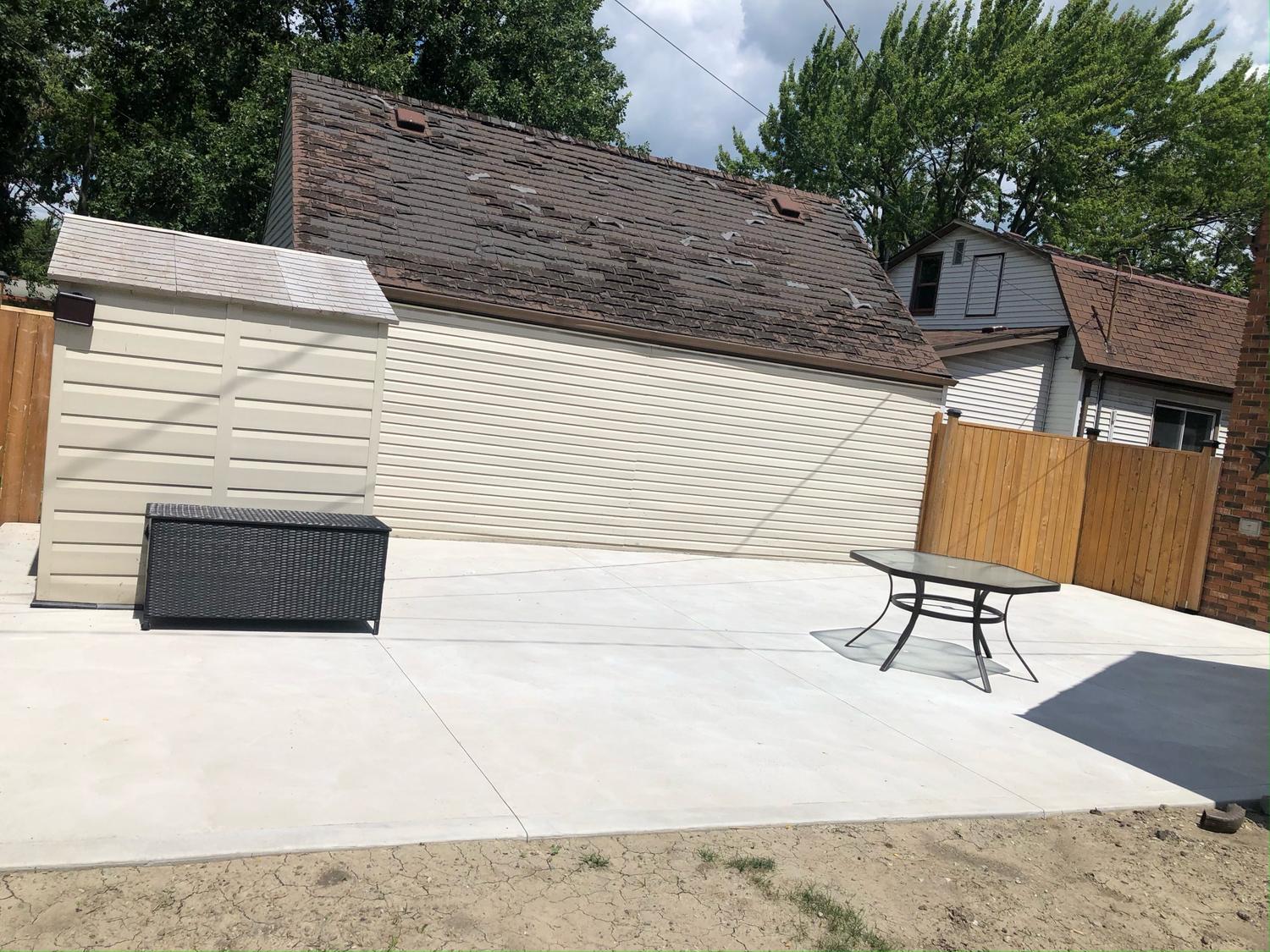 Concrete patio and shed pad behind a home
