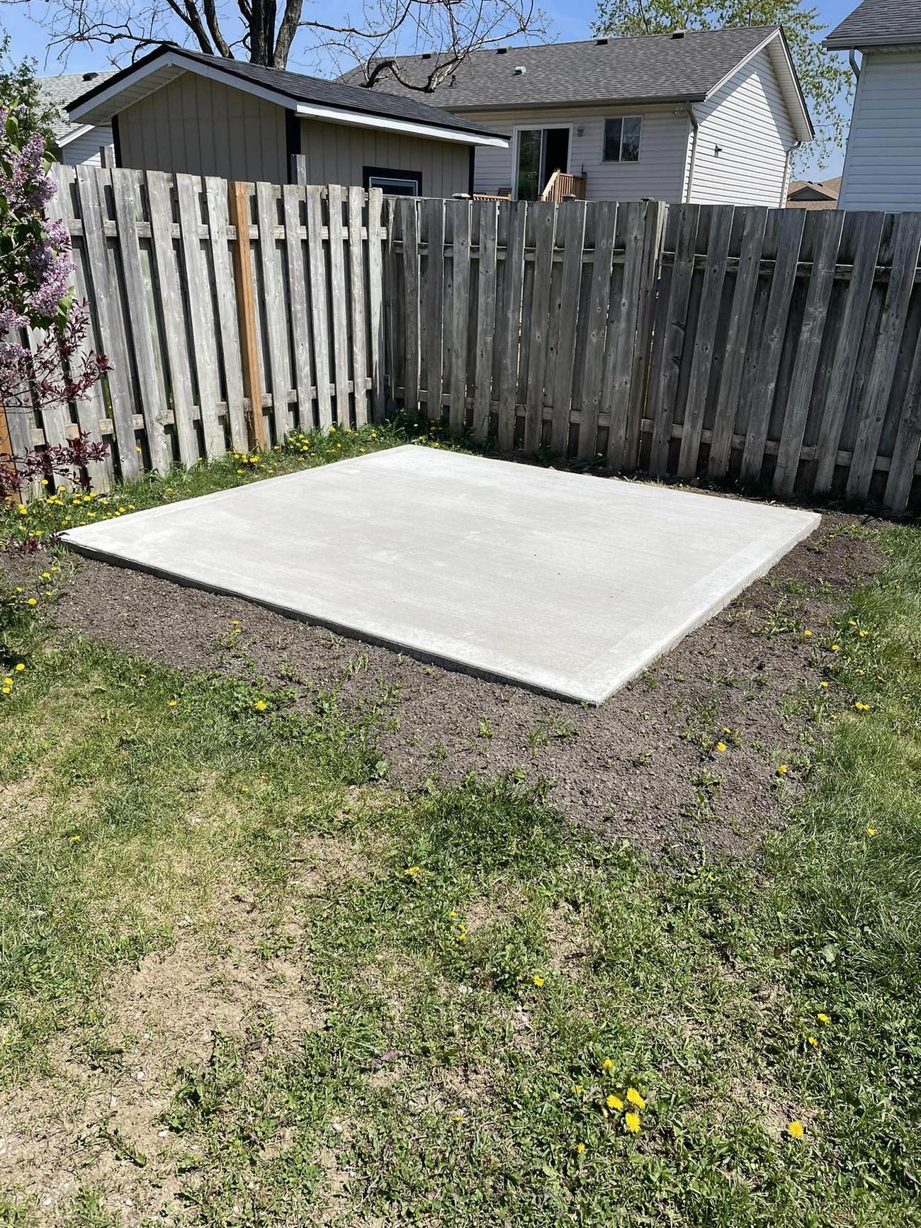 Square concrete shed pad in a backyard