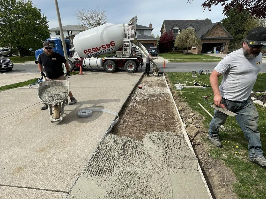 OTL crew placing concrete from the truck chute on a driveway pour