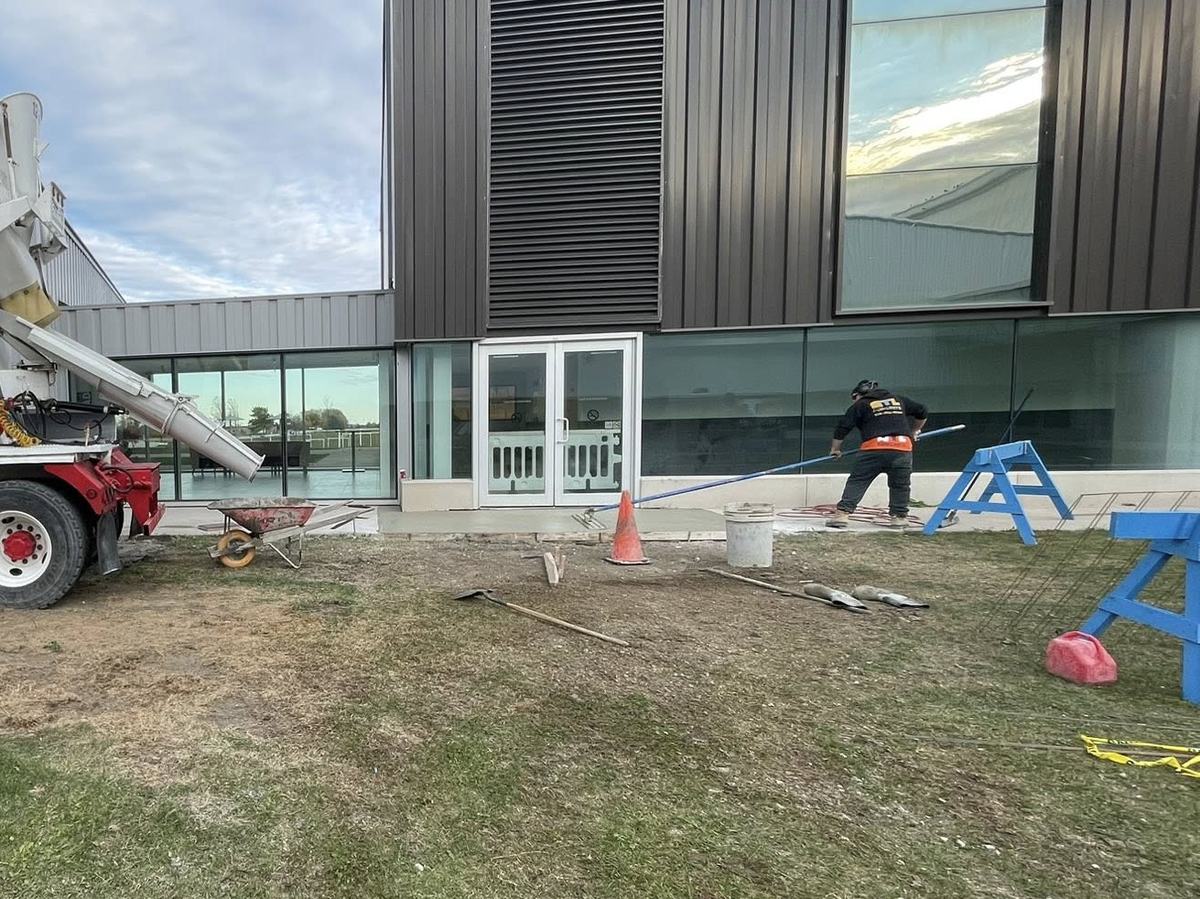 OTL crew finishing commercial concrete at a modern building