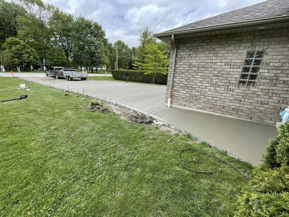 Broom-finished concrete driveway beside a brick home